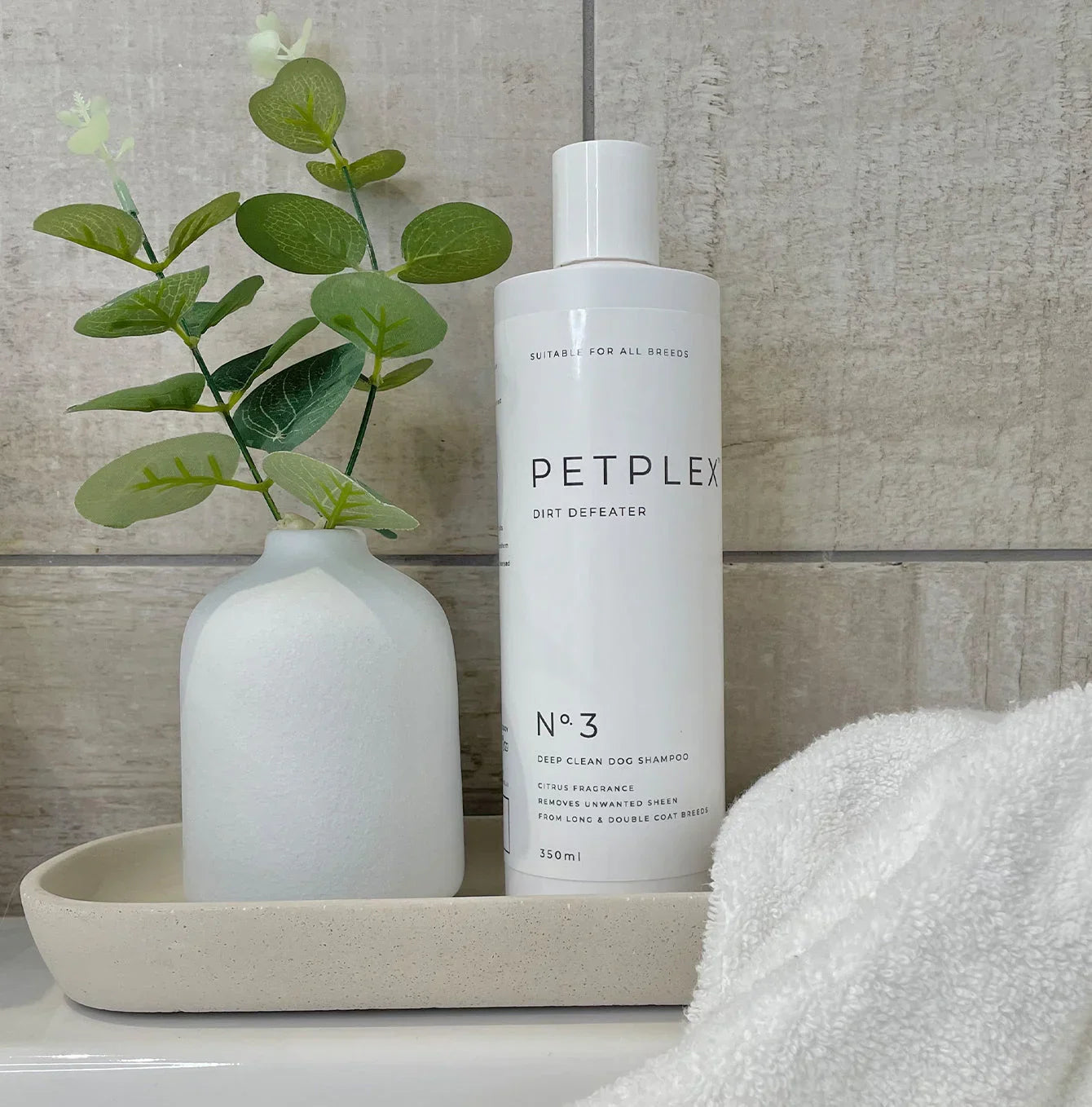 PetPlex No. 3 Dirt Defeater Deep Clean Dog Shampoo displayed on a bathroom tray with a towel and decorative vase