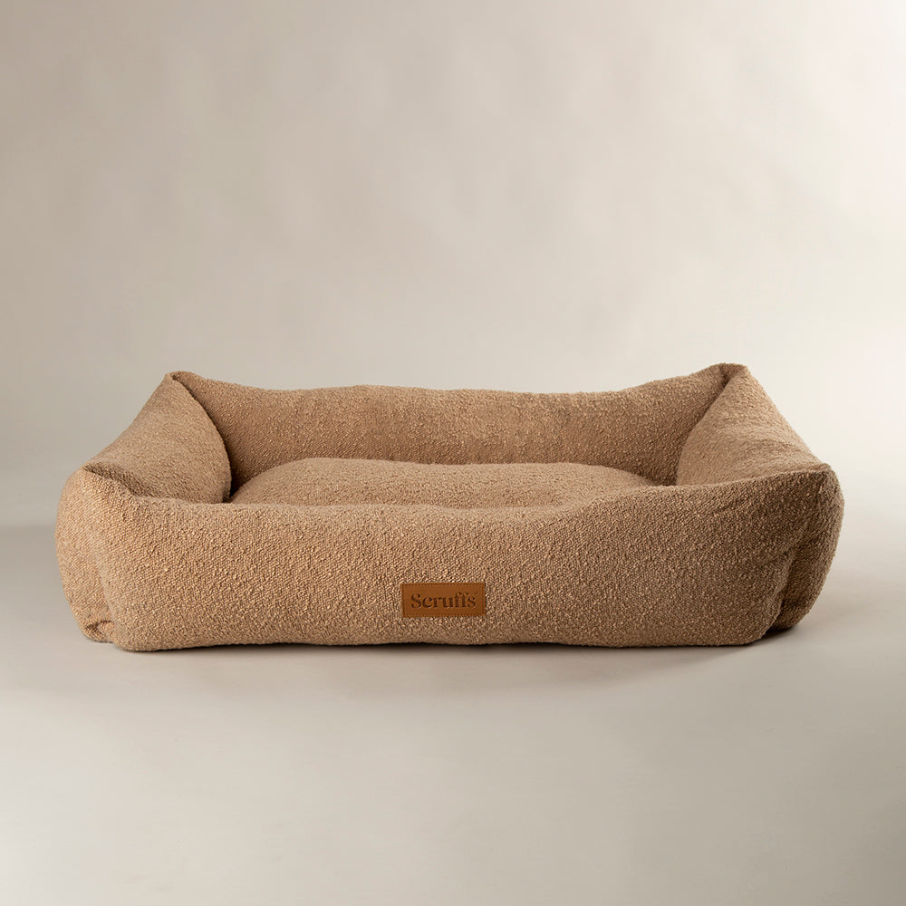 Beige dog bed with a brand label on a beige background