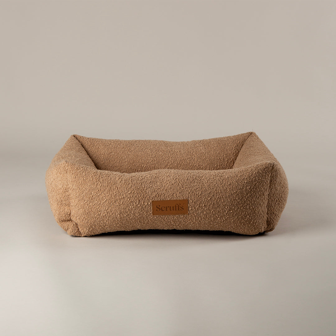 Beige pet bed with a brand label on a beige background