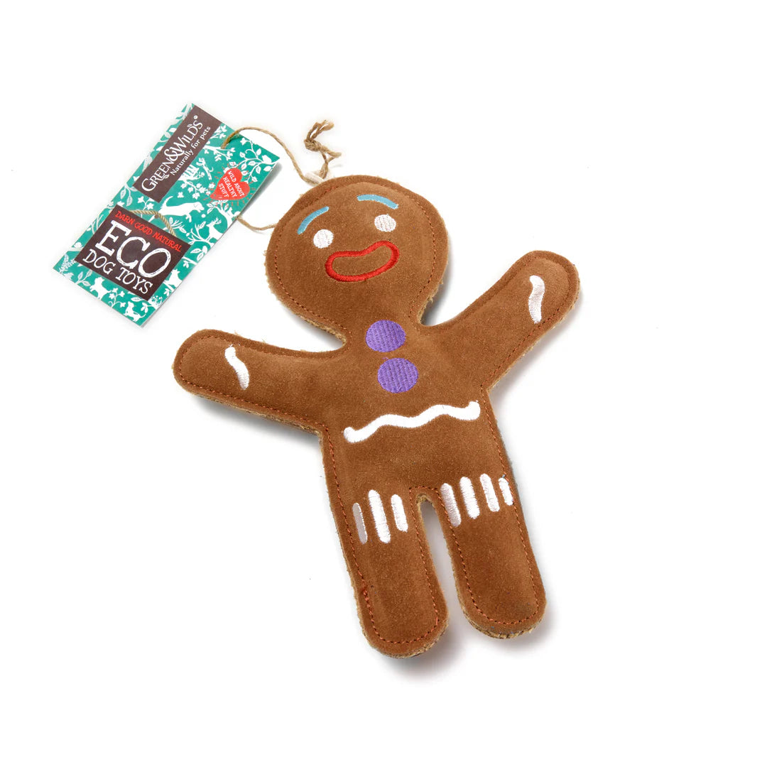 A brown gingerbread person-shaped eco dog toy with suede details, featuring a red and white face and purple buttons. It has a label attached that reads 'ECO DOG TOY'.