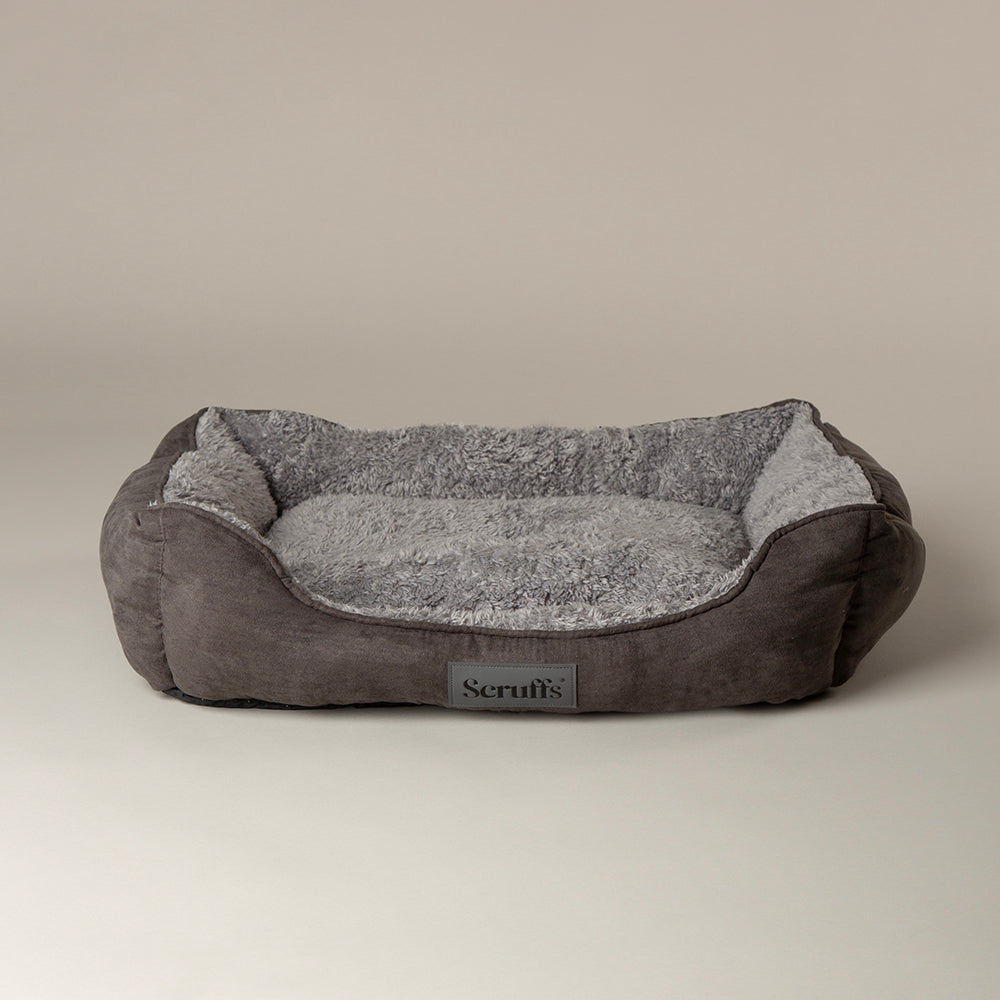 Grey soft dog bed with a textured surface on a beige background