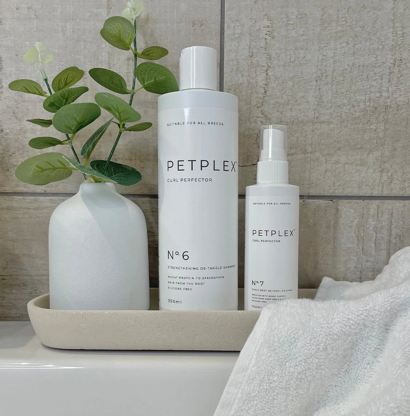 PetPlex curly coat dog shampoo and detangling spray on a bathroom tray
