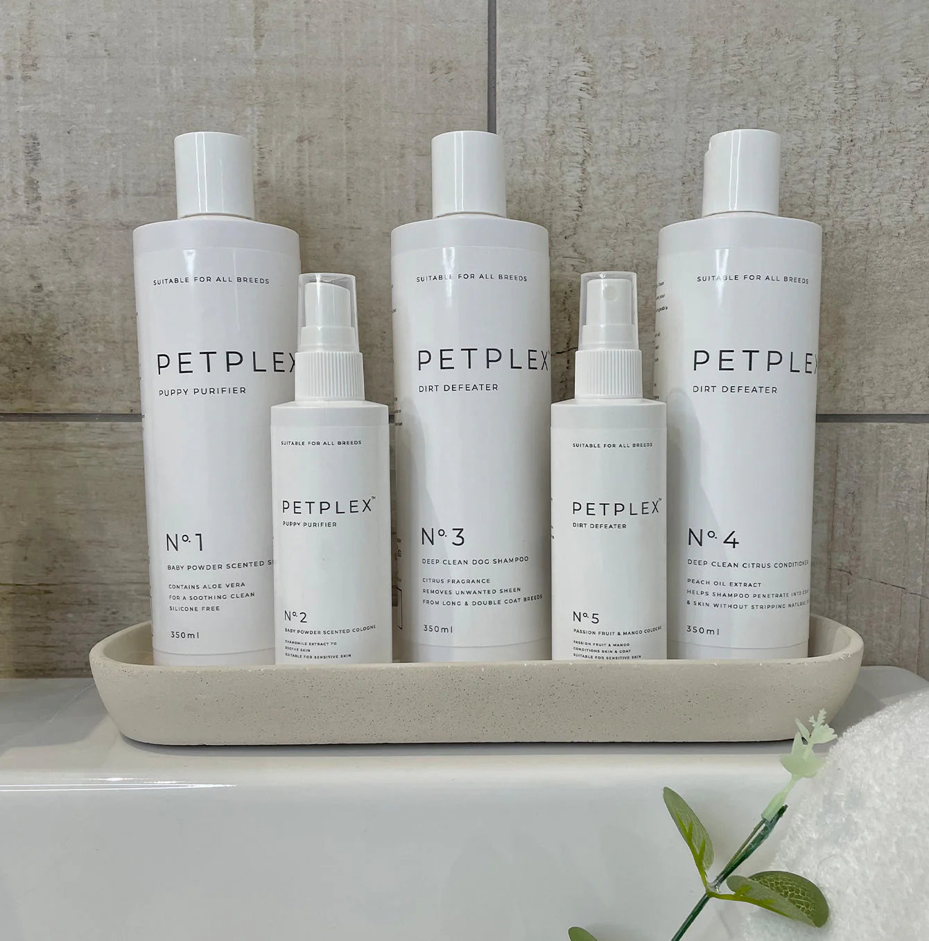 Set of Petplex pet care products, including the dirt defeater deep clean dog shampoo, dog conditioner, and dog cologne, all on a tray together with a neutral background 
