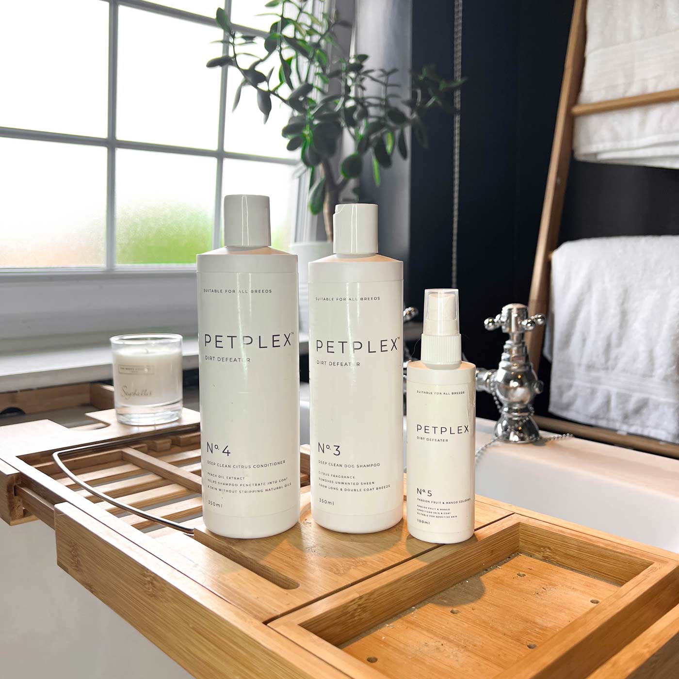 Three PetPlex products, including the dirt defeater deep clean dog shampoo, dog conditioner, and dog cologne, all on a wooden tray in a bathroom setting.
