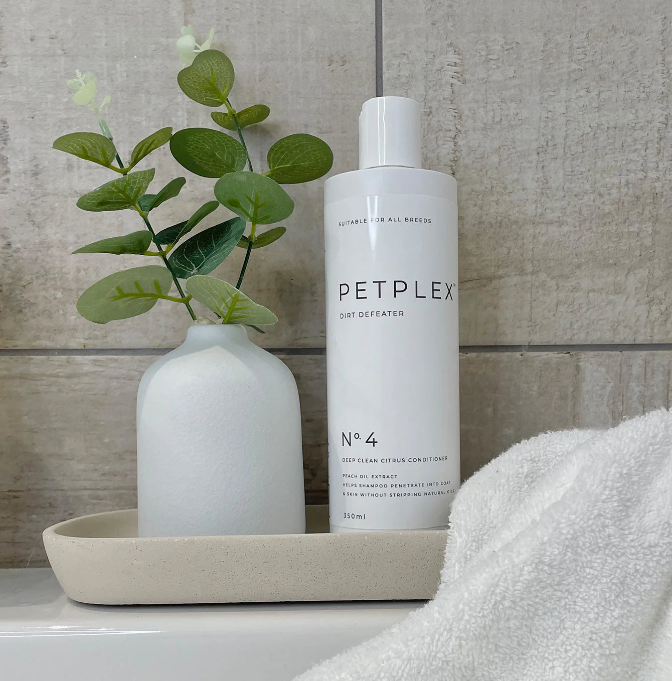 PETPLEX dog conditioner on a bathroom counter with a vase and plant