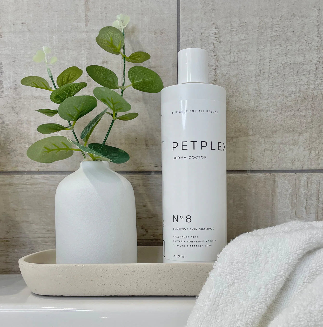 PetPlex No. 8 Derma Doctor Sensitive Skin Dog Shampoo displayed on a bathroom tray with a towel and decorative vase