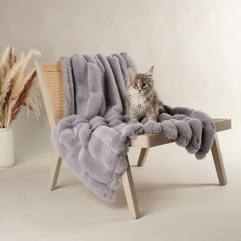 Grey faux fur blanket draped over a wooden chair.