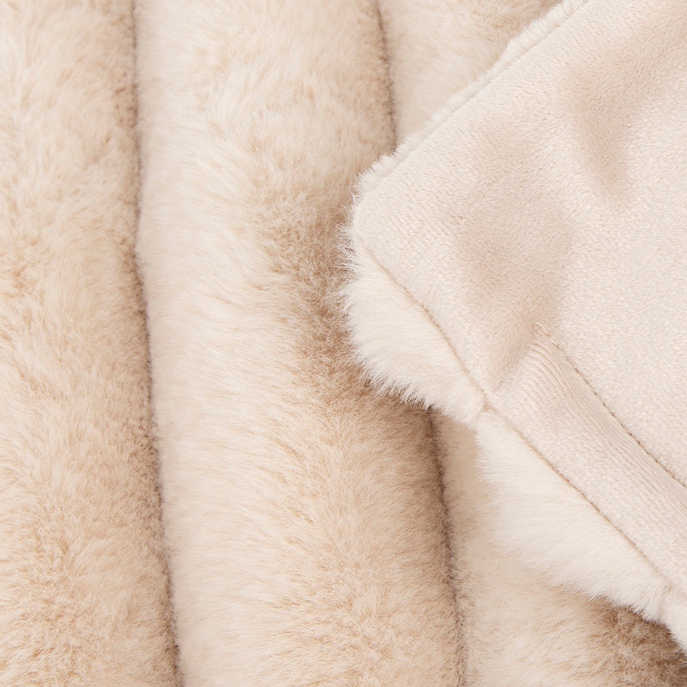 Close-up of cream faux fur blanket fabric texture.